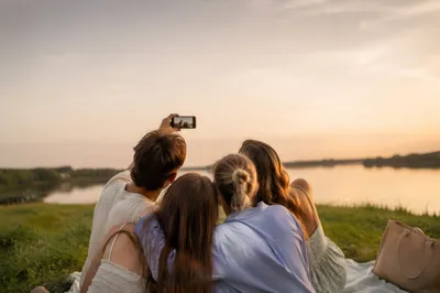 Friends Taking Playful Lakeside Selfie at Sunset