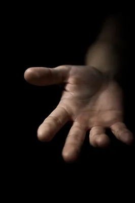 Open Hand Reaching in Dark Studio