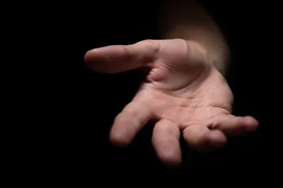 Open Hand Reaching in Dark Studio
