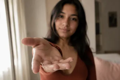 Woman Reaching Hand Toward Camera Indoors