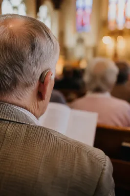 Older Person Wearing Hearing Aid in Pew