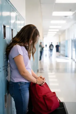 High School Student Praying by Lockers