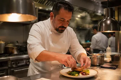 Hispanic Chef Plating Dish in Restaurant Kitchen