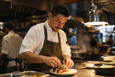 Hispanic Chef Plating Meal in Kitchen