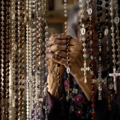 Hispanic Grandmother Holding Rosary in Prayer