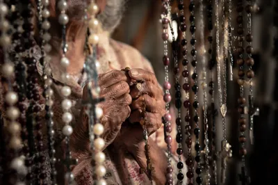 Hispanic Grandmother Holding Rosary in Prayer