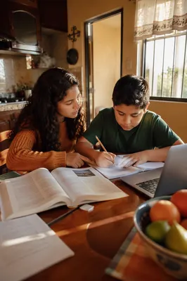 Hispanic Siblings Studying at Kitchen Table
