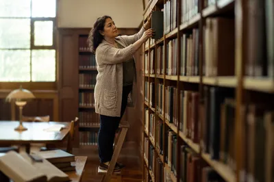Librarian Organizing Books in Quiet Reading Room