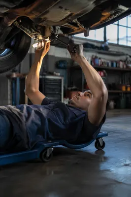 Mechanic Working Beneath Raised Car
