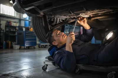 Mechanic Working Beneath Raised Car