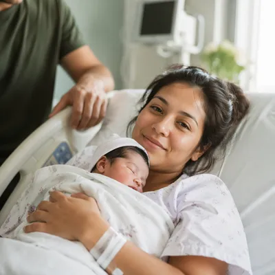 Mother Cradling Newborn in Hospital Bed