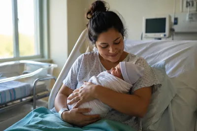 Mother Holding Newborn in Hospital Room