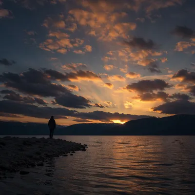 Silhouetted Prayer by Dramatic Sunset Lake