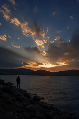 Silhouetted Prayer by Dramatic Sunset Lake