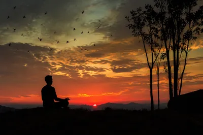 Meditative Silhouette Under Dramatic Sunset Sky