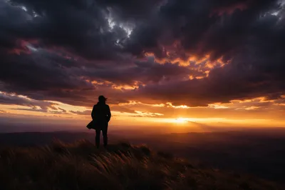 Silhouetted Person on Hill at Sunset