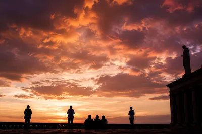 Silhouetted People Praying Beneath Dramatic Sunset