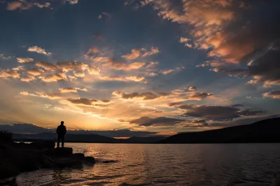 Silhouetted Figure Praying by Sunset Lake