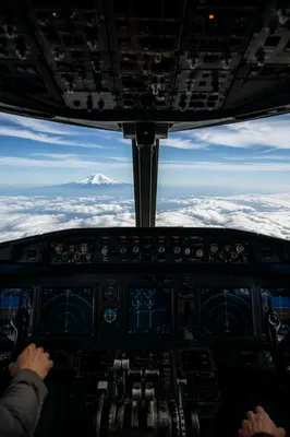 Pilot Hands in Airplane Cockpit Above Clouds