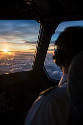 Pilot in Cockpit Above Sunrise Clouds