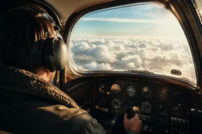 Pilot in Vintage Cockpit Above Clouds