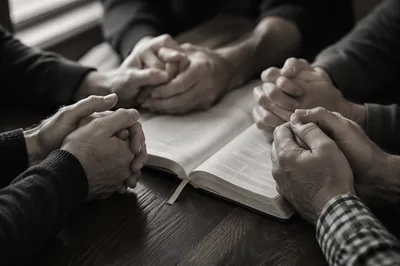 Adult Hands in Prayer Around Book