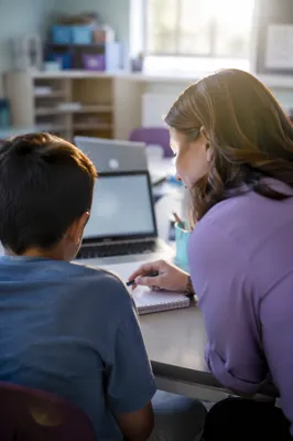Teacher Supporting Student in Bright Classroom