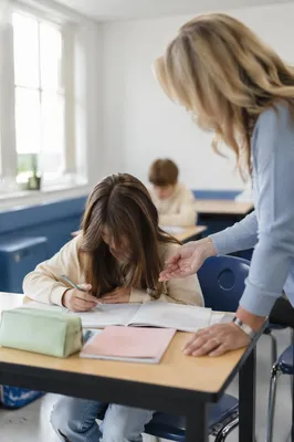 Teacher Assisting Student in Bright Classroom