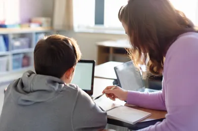 Teacher Supporting Student in Bright Classroom