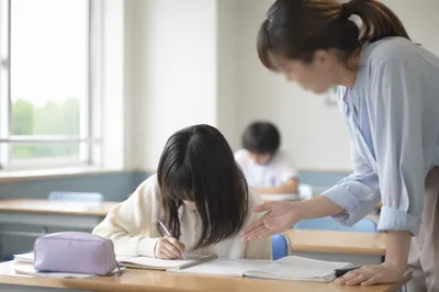 Teacher Assisting Student in Bright Classroom