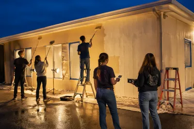 Teen Volunteers Painting Community Building at Dusk