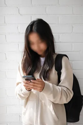 Teen Student Checking Phone by White Wall