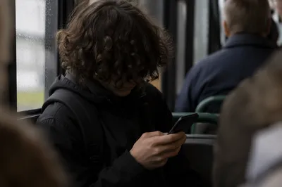 Teen Student Browsing Phone on Rainy Commute