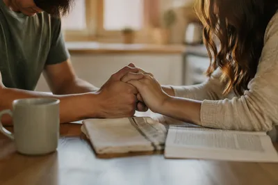 Young Couple Praying at Kitchen Table