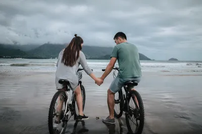 Young Couple Praying by Ocean Bicycles