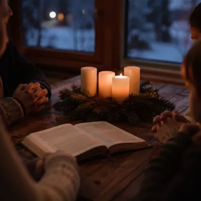 Family Hands Around Advent Candle Table