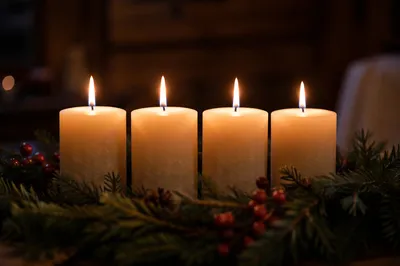 Four Lit Advent Candles in Evergreen Wreath