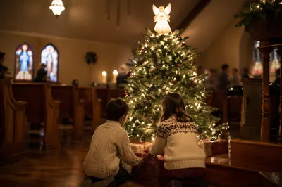Children Placing Gifts Beneath Christmas Angel Tree