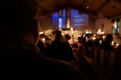 Raised Candle in Christmas Eve Congregation