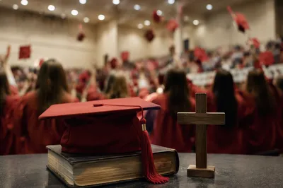 Red Graduation Cap on Bible and Cross