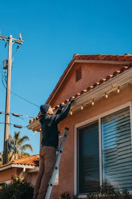 Hanging Christmas Lights on Suburban Rooftop