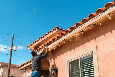 Hanging Christmas Lights on Suburban Rooftop