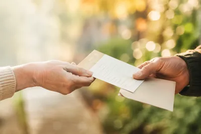 Hands Exchanging Stewardship Pledge Card Outdoors