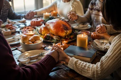 Thanksgiving Family Prayer Around Rustic Dinner Table