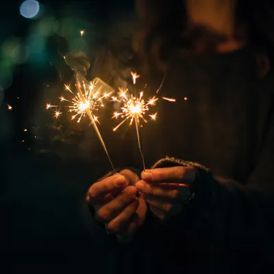 Hands Holding Sparklers at Night Celebration