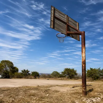 Weathered Rural Basketball Hoop Under Blue Sky