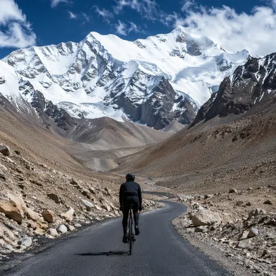 Lone Cyclist Climbing Snowy Mountain Road