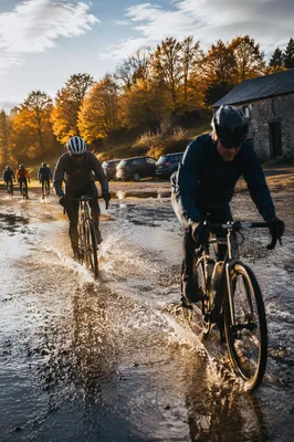 Cyclists Splashing Through Autumn Trail Puddle