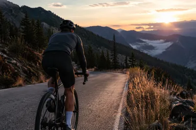 Road Cyclist Climbing Mountain at Sunrise