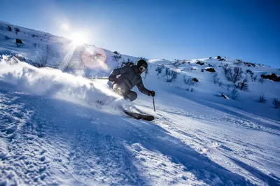 Downhill Skier Carving Powder on Sunlit Mountain
